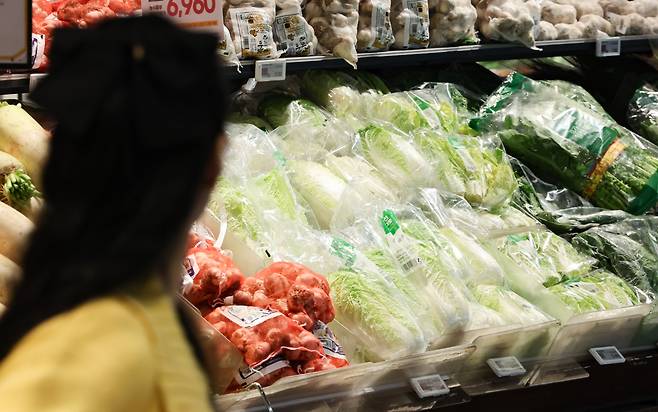 A shopper passes by a display of kimchi ingredients, including napa cabbage and garlic, at a market in Seoul. (Newsis)