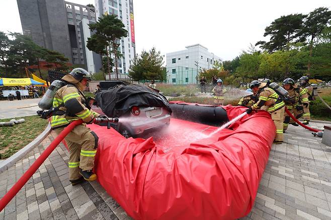 29일 오후 서울 금천구 디폴리스 지식산업센터에서 지하철 전기차 화재 발생 상황을 가정해 열린 '2024 금천구 긴급구조종합훈련 & 재난대응 안전한국훈련'에서 소방대원이 이동식 수조를 이용해 전기차 화재를 진압하고 있다. 연합뉴스