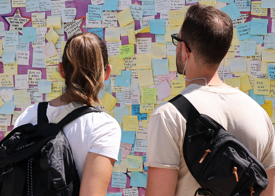 Foreigners read messages posted by visitors of the joint memorial altar, previously located at Seoul Plaza in central Seoul, on June 16. [NEWS1]