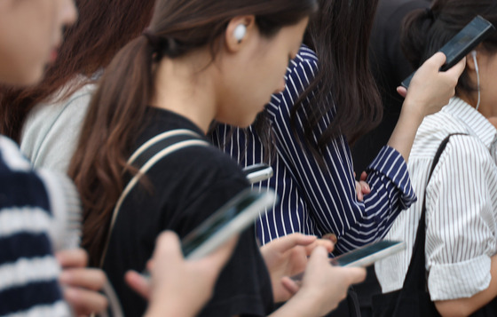 Commuters look at their phones on a Seoul subway on Sept. 19. [YONHAP]