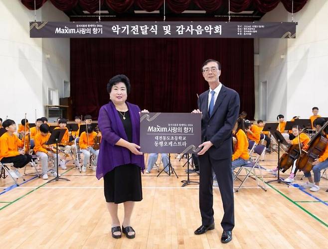 최상인 동서식품 홍보상무(오른쪽)와 대전동도초등학교 강창숙 교장이 31일 대전 대덕구 대전동도초등학교에서 열린 '제17회 맥심 사랑의 향기' 행사에서 기념촬영하고 있다.[사진제공=동서식품]