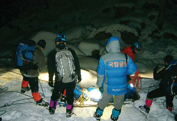 설악산은 아름다움과 위험이 함께하는 산이다. 야간의 고지대 눈밭에서 조난자를 들것에 결박하고 하산 준비를 하고 있는 레인저들. 사진 설악산국립공원사무소.