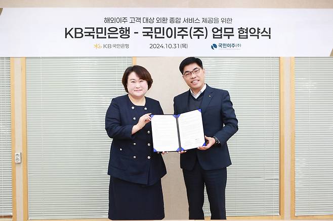 김지영(왼쪽) 국민이주(주) 대표와 이상신 KB국민 은행 외환사업본부장이 기념 촬영을 하고 있다. [KB국민은행 제공]