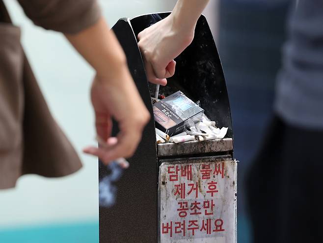 Smokers dispose of their cigarette butts at a smoking zone in Jongno District, central Seoul, on Aug. 14. [NEWS1]