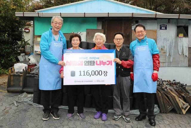 임종룡(왼쪽 첫 번째) 우리금융그룹 회장, 장광익 우리금융그룹 부사장(왼쪽 네 번째)이 지난 1일 서울 성북구 취약계층 가정집에 연탄 배달을 한 후 마을 주민들과 기념 촬영을 하고 있다. /우리금융그룹