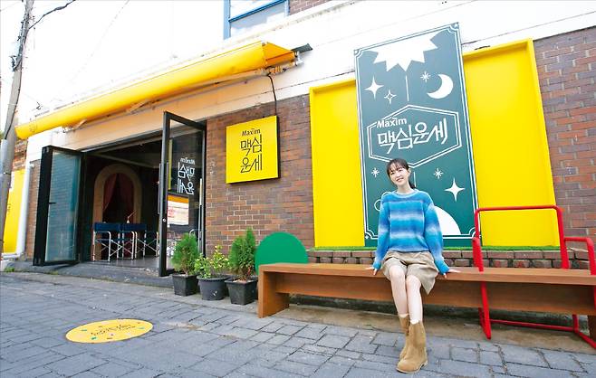 맥심 모델인 배우 박보영이 맥심골목 내 ‘맥심운세’ 앞 벤치에 앉아 있다.  동서식품 제공