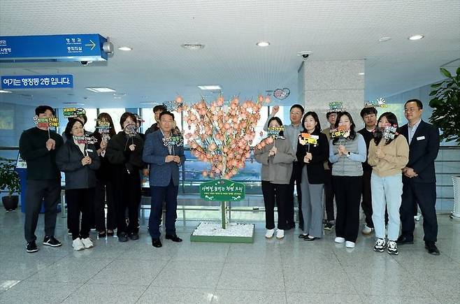 [창원=뉴시스] 강경국 기자 = 정현섭 경남 창원시 진해구청장과 구청 직원들이 행정동 2층에 있는 사계절 꽃피는 청렴트리를 단풍잎으로 단장한 후 기념촬영을 하고 있다. (사진=창원시청 제공). 2024.11.06. photo@newsis.com  *재판매 및 DB 금지