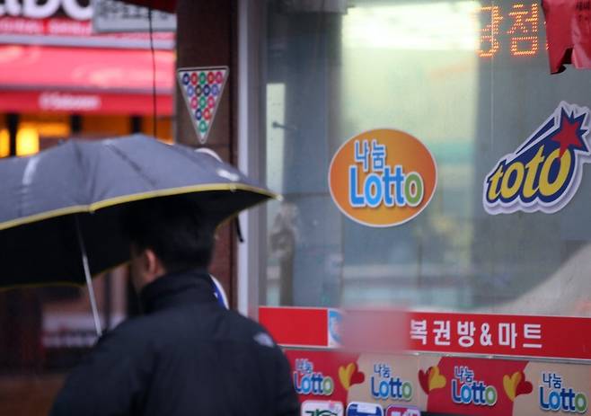 한 시민이 로또, 스포츠토토 등을 판매하는 복권판매점 앞을 지나고 있다. /연합뉴스
