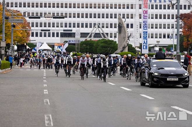 [창원=뉴시스]'투르 드 경남 2024 스페셜대회’ 참가 선수들이 대회 마지막 날인 10일 오전 경남도청 광장에서 힘차게 출발하고 있다. 창원 경기는 도청광장~창원시청 앞 광장 구간을 13회전(총 39㎞)하는 크리테리움 방식(도심 단거리 순환방식)으로 진행됐다.(사진=경남도 제공) 2024.11.10. photo@newsis.com