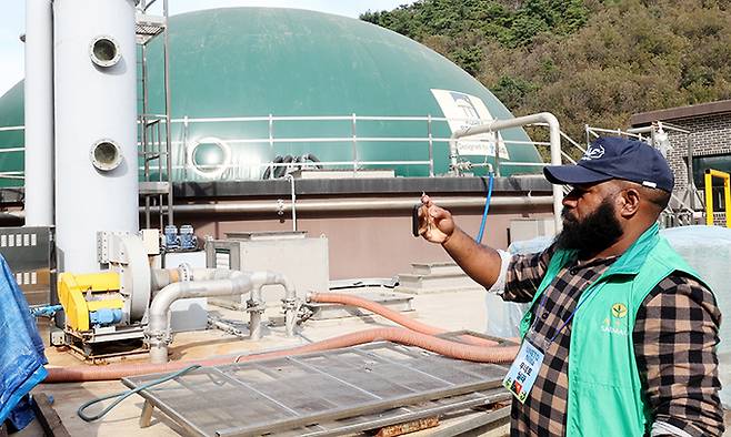 파푸아뉴기니 은가이 베나 주 환경미화 및 역량강화부 관리자인 우네토 닐라(28)씨가 가축분뇨자원화 시설을 카메라에 담고 있다.