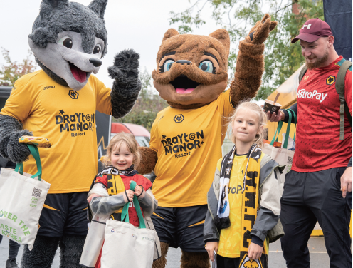 9월 15일 영국 ‘몰리뉴 스타디움’ 앞 ‘치즈맛 불닭볶음면’ 등 한국 스낵 보따리를 받아든 울버햄튼 원더러스 FC의 늑대 마스코트와 팬. / aT