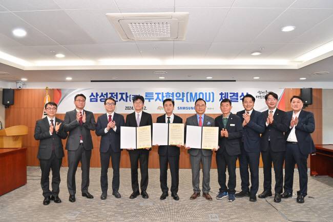 김태흠(왼쪽  다섯 번째) 충남지사, 박상돈(오른쪽 다섯 번째) 천안시장, 남석우(왼쪽 네 번째) 삼성전자 사장이 12일 충남도청 상황실에서 고대역폭 메모리(HBM) 천안 투자협약을 체결한 뒤 기념 촬영을 하고 있다.  충남도청 제공