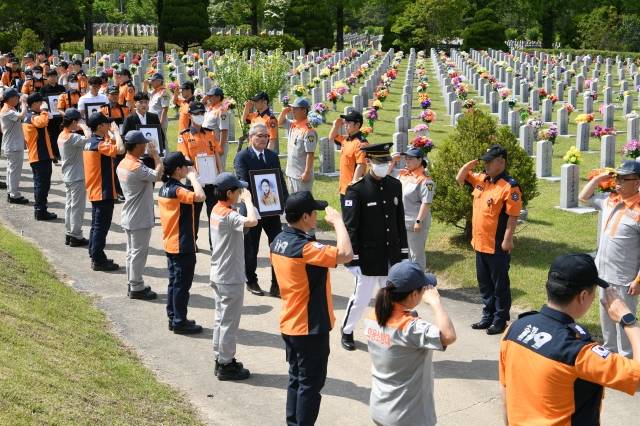 순직 소방공무원 합동안장식이 지난해 5월 25일 국립대전현충원 소방공무원묘역에서 소방공무원들의 경례 속에 진행되고 있다. 연합뉴스