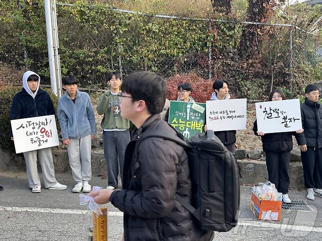 2025학년도 대학수학능력시험이 치러지는 충북 충주고등학교로 한 수험생이 무거워 보이는 가방을 맨 채 후배들의 응원을 받으며 긴장스런 표정으로 입장하고 있다.2024.11.14/뉴스1 ⓒ News1 윤원진 기자