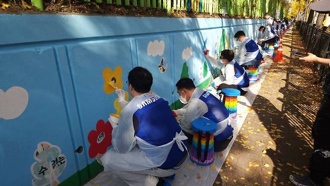 삼성전자 임직원들이 12일 수원시 권선구 구운초등학교에서 벽화 그리기 봉사 활동에 참여하고 있다.ⓒ삼성