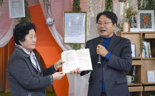 강기정 광주광역시장이 13일 오후 동구 전일빌딩245 ‘북카페, 소년이 온다’ 오픈행사에 참석해 ‘소년이 온다’의 주인공 ‘동호’의 모티브가 된 문재학 열사의 어머니 김길자씨로부터 책을 기증받고 있다./사진=광주시