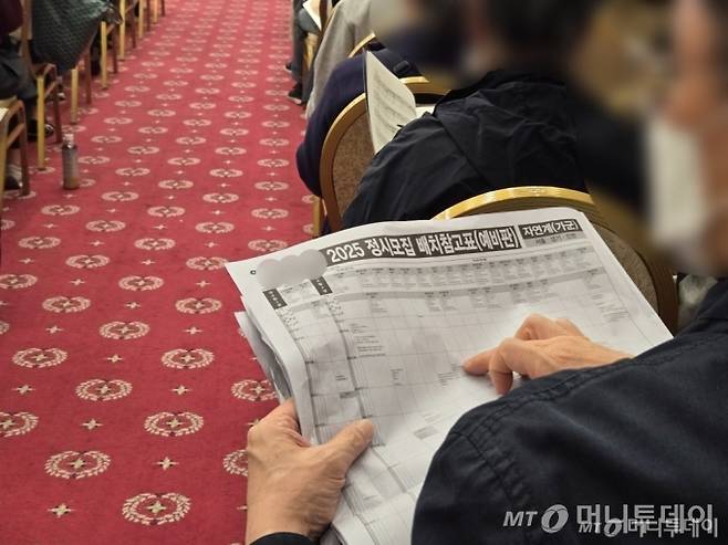 수능 다음날인 15일 오후 3시. 2025학년도 대학수학능력시험 이후 사립학원에서 개최한 대학 입시설명회에서 한  남성이 정시모집 배치 참고표를 펼치고 손가락으로 짚으며 읽고 있다 /사진=이혜수 기자
