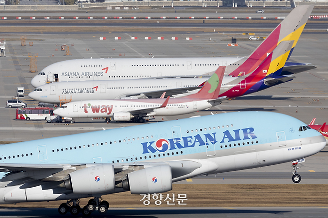 지난해 11월2일 인천국제공항 주기장에 서 있는 아시아나 여객기 앞으로 대한항공 여객기가 날아오르고 있다. 문재원 기자