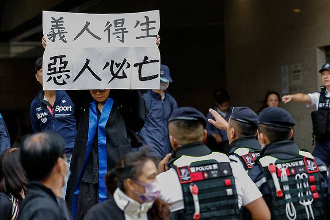 입법회 선거에 출마해 국가전복을 꾀했다는 이른바 ‘홍콩 47’ 사건으로 중형을 선고받은 헨드릭 루이의 어머니 엘사 우가 19일 홍콩 서구룡 치안법원에서 아들의 선고 공판이 이뤄지는 동안 ‘의인득생 악인필망(義人得生 惡人必亡)이라고 적힌 손팻말을 펼쳐 들고 있다. 엘사 우도 이날 체포됐다. /로이터연합뉴스