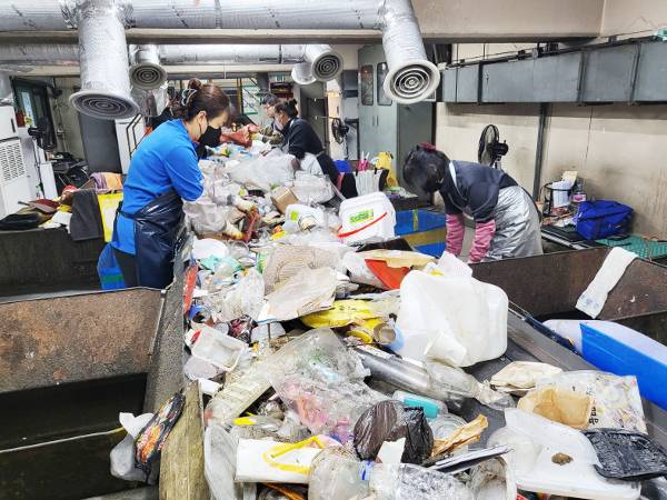 경기 구리시 자원회수시설 내 재활용 선별장에서 7일 선별원들이 앞치마와 마스크, 장갑을 끼고 재활용 가능한 물품을 쓰레기 더미에서 골라내고 있다.