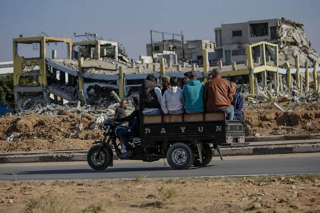 가자지구 중심부 알마가지 난민 캠프에서 파괴된 건물을 지나가고 있는 사람들. / EPA 연합뉴스