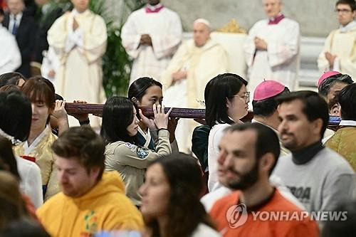 세계청년대회 상징물 전달식 (바티칸 AFP=연합뉴스) 24일(현지시간) 바티칸 성 베드로 대성전에서 열린 '세계 청년의 날' 미사 말미에 한국 청년 대표단이 포르투갈의 청년들로부터 세계청년대회 상징물인 나무 십자가를 전달받고 있다. 2024.11.24 photo@yna.co.kr