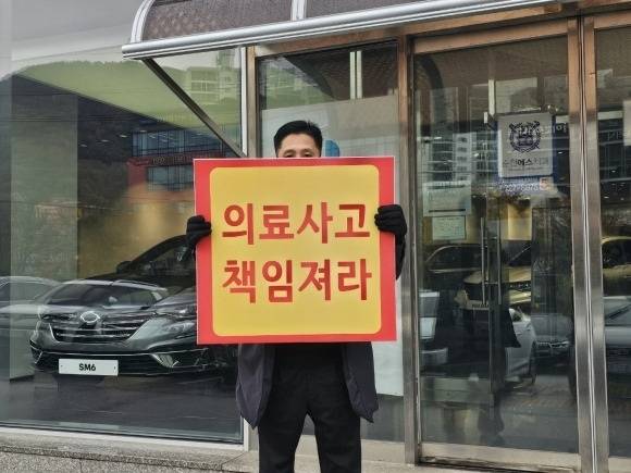 순천 모 치과 앞에서 전신마비 증상을 호소하는 환자의 가족이 피켓시위를 벌이고 있다.