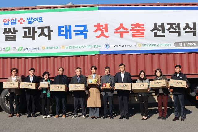 김영우 충북 청주 청원생명쌀조공법인 의장(왼쪽 다섯번째)이 황종연 충북농협본부장(〃 여덞번째) 등 관계자와 함께 태국으로 첫 수출길에 오르는 ‘안심쌀이요’ 쌀 과자를 들어보이고 있다.