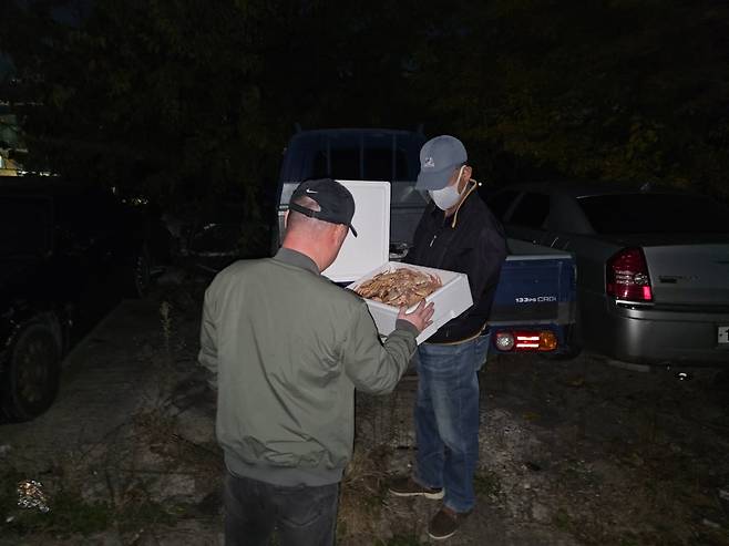 지난 17일 오후 10시 경북 안동의 한 변두리 주차장에서 ‘빵게’ 밀매업자가 손님에게 스티로폼 상자 뚜껑을 열어 보이며 살아있는 상태를 확인시켜주고 있다. /독자제공