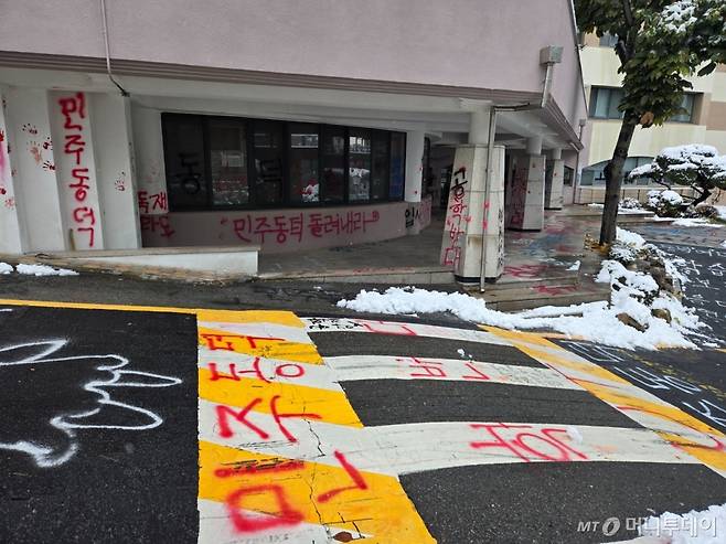동덕여대 율동기념음악관 외벽과 도로에 래커로 '민주동덕'이 붉게 쓰여있다. 빨간 손바닥 자국도 수십개 찍혀있다.