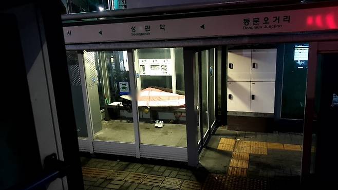 방풍 시설이 설치된 서귀포시의 한 버스정류장 온열 의자 위에서 이불을 덮고 잠을 자는 한 남성 (사진, 제주자치도에 바란다)