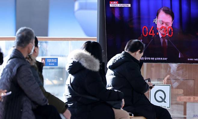 4일 오후 서울역 대합실에서 시민들이 윤석열 대통령의 비상계엄 선포·해제 관련 뉴스를 시청하고 있다. 뉴스1
