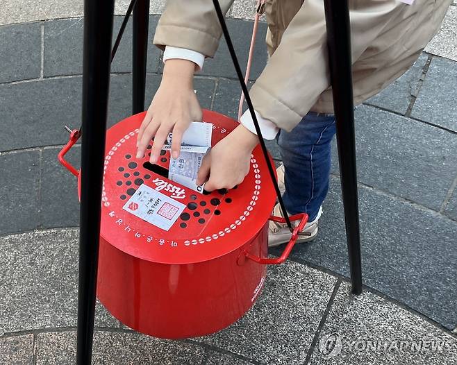 구세군 자선냄비에 기부하는 김설아(10) 양 (서울=연합뉴스) 지난 4일 서울 명동예술극장 앞 구세군 자선 냄비에 김설아(10) 양이 성금을 내고 있다. 2024.12.7. [촬영 오인균]