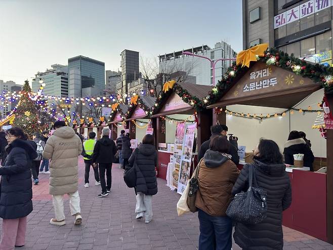 지난 6일 홍대 레드로드에서 열린 '12월 동행축제' 참여 부스 앞을 방문객들이 지나가고 있다. 사진=신지민 기자