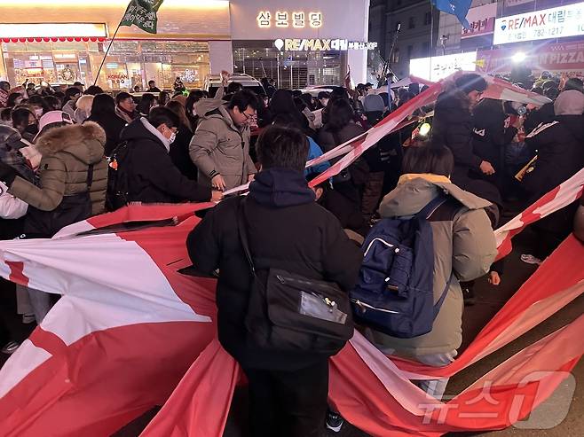 9일 오후 8시 50분쯤 서울 여의도 국민의힘 중앙당사 앞에서 시민들이 국민의힘 플래카드를 찢는 퍼포먼스를 하고 있다. 2024.12.9/뉴스1