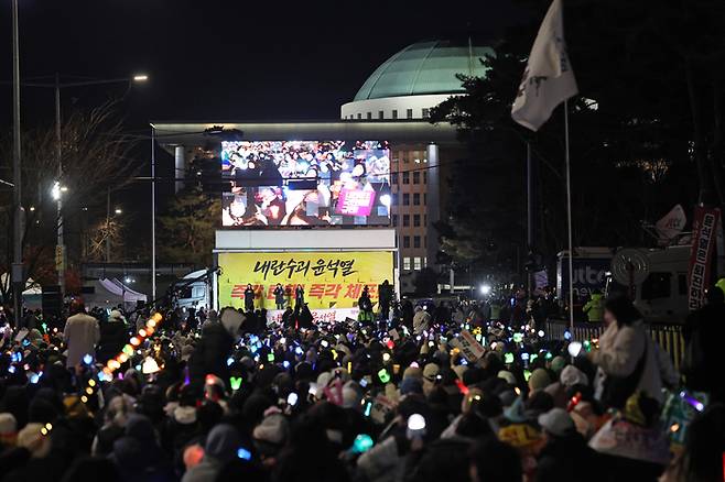 8일 오후 서울 여의도 국회 앞에서 열린 윤석열 탄핵 및 구속을 촉구하는 촛불집회에서 참가자들이 관련 손팻말과 응원봉을 들고 있다. 연합뉴스