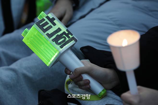 윤석열 대통령에 대한 탄핵소추안 표결이 진행된 7일 서울 여의도 국회앞에서 열린 ‘범국민촛불대행진’ 참가자가 ‘탄핵’ 글자가 적힌 아이돌 NCT 응원봉과 촛불을 들고 있다. 정효진 기자