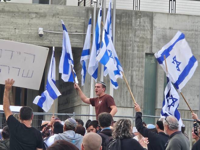 10일 베냐민 네타냐후 이스라엘 총리의 비리 혐의 재판이 열린 텔아비브 법원 앞에서 네타냐후 지지자들이 이스라엘 국기를 흔들며 노래를 부르고 있다./김지원 특파원