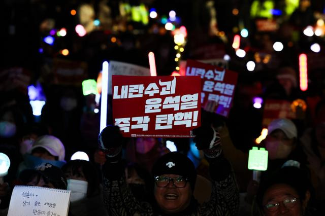 10일 오후 서울 여의도 국회 앞에서 열린 시민촛불집회에 참석한 사람들이 '내란수괴 윤석열 즉각 탄핵!' 손팻말을 들고 구호를 외치고 있다. 뉴시스