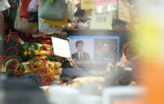 지난 8일 오전 대구 중구 서문시장에서 한 상인이 '계엄 사태'관련 뉴스를 보고 있다. 연합뉴스