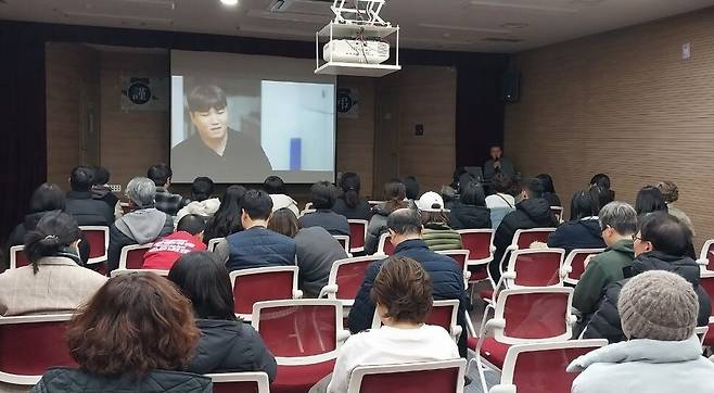 지난 5일 저녁 고 강태완씨가 안치된 전북 익산 원광대병원 인근 유스호스텔에서 그를 추모하는 사람들이 모여 태완씨의 생전 인터뷰 영상을 보고 있다. 금속노조 전북지부 제공