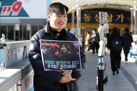 서문시장 육교 위에서 윤 대통령 퇴진 촉구 집회를 안내하고 있는 청년 유튜버. [뉴스1]