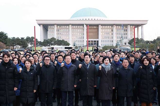 더불어민주당 이재명 대표와 박찬대 원내대표(오른쪽 세 번째), 김민석 수석최고위원(왼쪽 세 번째)을 비롯한 의원들이 탄핵안 표결을 앞둔 12월7일 국회 앞에서 구호를 외치고 있다. ⓒ연합뉴스