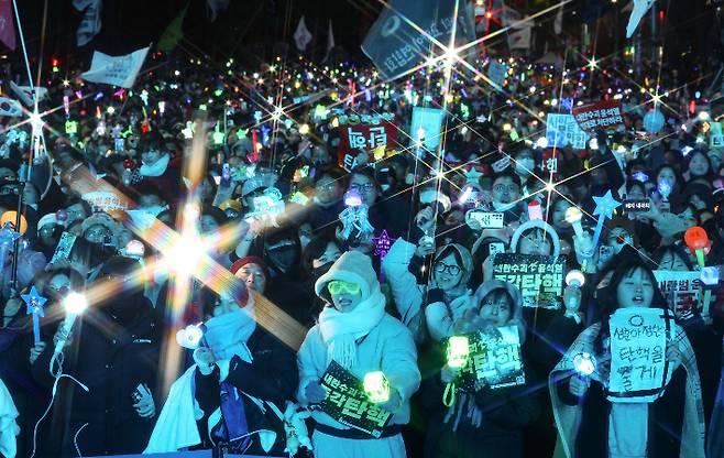 윤석열 대통령 탄핵소추안이 가결된 14일 서울 여의도 국회 앞에서 열린 촛불집회에 참석한 시민들이 환호하고 있다.  연합뉴스