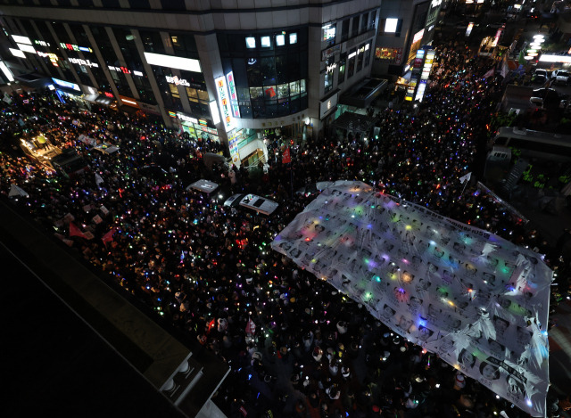 12일 오후 서울 영등포구 국민의힘 당 사무실 앞에서 열린 윤석열 대통령 탄핵 촉구 촛불 집회 행진에 참석한 시민들이 윤 대통령의 탄핵소추안 투표에 불참한 국민의힘 의원들을 규탄하는 현수막을 들어올리고 있다. 연합뉴스