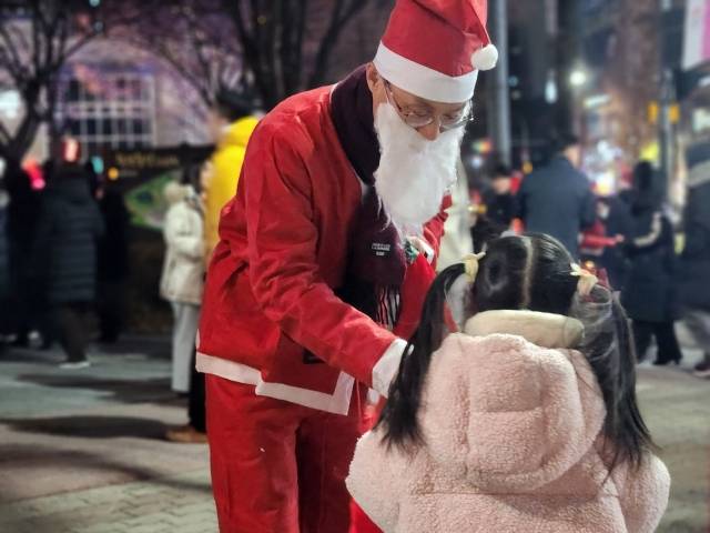산타 차림을 한 새에덴교회 교인이 죽전중앙공원 일대에서 지역 아이에게 성탄 선물을 건네고 있다.
