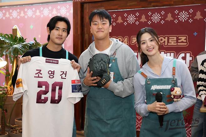 키움 김건희(가운데)가 15일 서울 마곡동에 위치한 한 카페에서 열린 '2024 키움 히어로즈 연말자선행사'에서  조영건(왼쪽)의 글러브와 유니폼을 낙찰받고 미소 짓고 있다. /사진=키움 히어로즈 제공