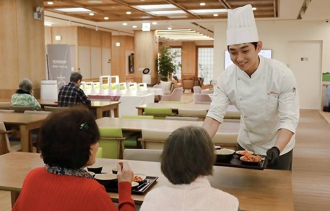 삼성웰스토리 조리사가 경기도 성남시 분당구에 문을 연 신한라이프케어 1호 사업장인 ‘분당데이케어센터’에서 시니어들에게 식사를 제공하고 있다. <삼성웰스토리>