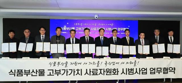 17일 서울 중구 이마트 본사에서 열린 ‘식품부산물 고부가가치 사료자원화 시범사업 업무협약식’에서 참여 기관·단체 12곳 관계자들이 협약서를 들어 보이고 있다. 농림축산식품부