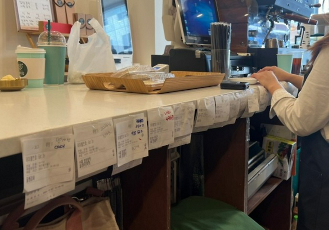 지난 9일 국회 앞에 위치한 한 카페 조리대에 수십개의 선결제 주문내역 영수증이 걸려있다. 연합뉴스